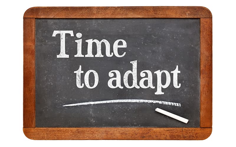 Blackboard with the words "Time to adapt" written on it